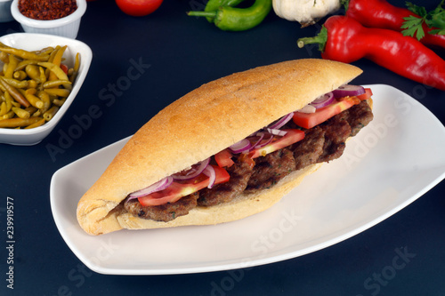 Delicious Turkish Meatballs Sandwich, Kofte Ekmek. Ingredients with bread crumbs, butter, sliced onion, parsley, tomato, pickles and seasoning spices. Hamburger serving on wood table background. 