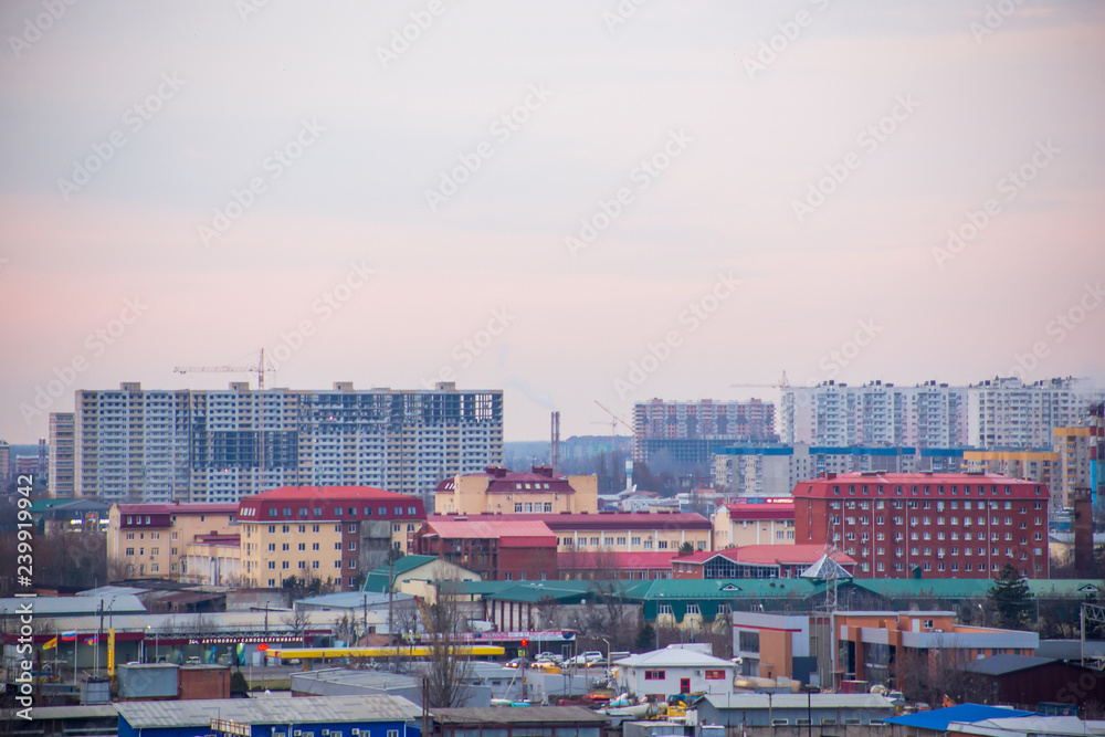 Landscape of evening city with high-rise buildings under construction, factories and pipes with smoke at sunset under boundless cloudy sky Landscape of evening city with high-rise buildings under construction, factories and pipes with smoke at sunset under boundless cloudy sky