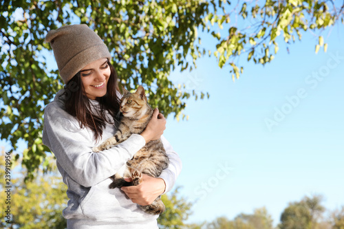 Young woman with cute stray cat outdoors. Space for text