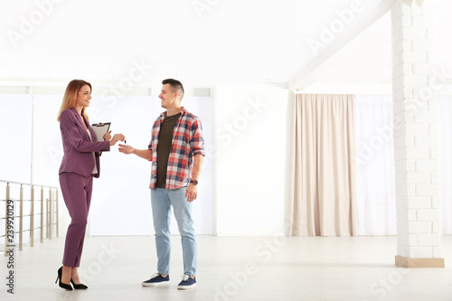 Real estate agent giving apartment keys to client indoors. Space for text
