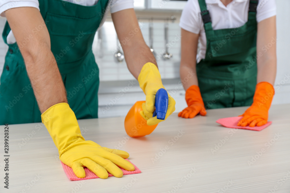 Team of janitors cleaning table in kitchen, closeup Team of janitors cleaning table in kitchen, closeup