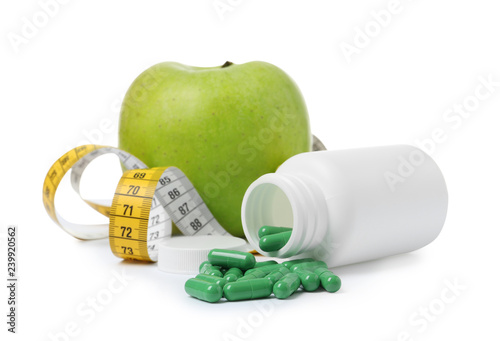 Weight loss pills, bottle, apple and measuring tape on white background