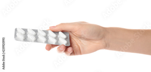 Woman holding pills in blister pack on white background, closeup