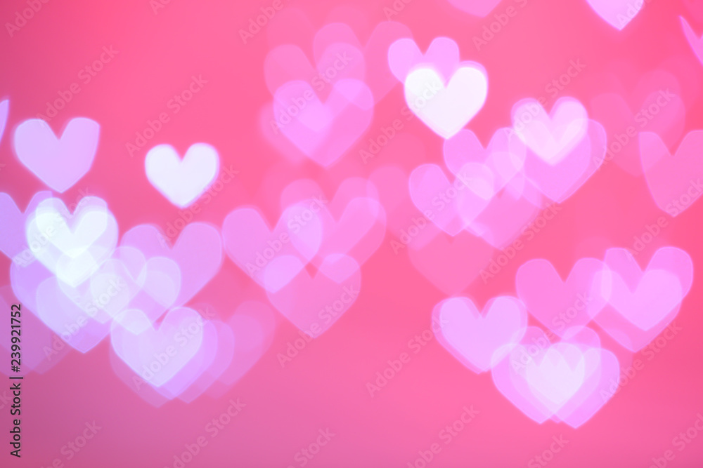 Blurred view of beautiful heart shaped lights on color background