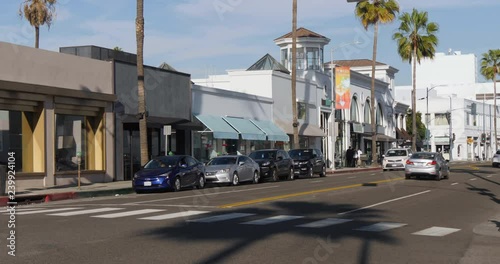 A daytime exterior establishing shot of traffic in the upscale shopping district near Rodeo Drive in Beverly Hills. Store names obscured for general stock use.  	