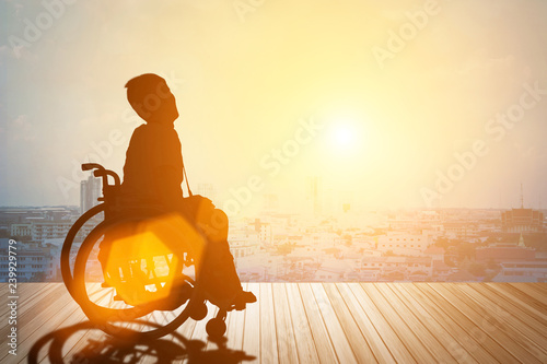 Obraz na plátne Young disabled asian man in wheelchair against wheelchair sunset and city background