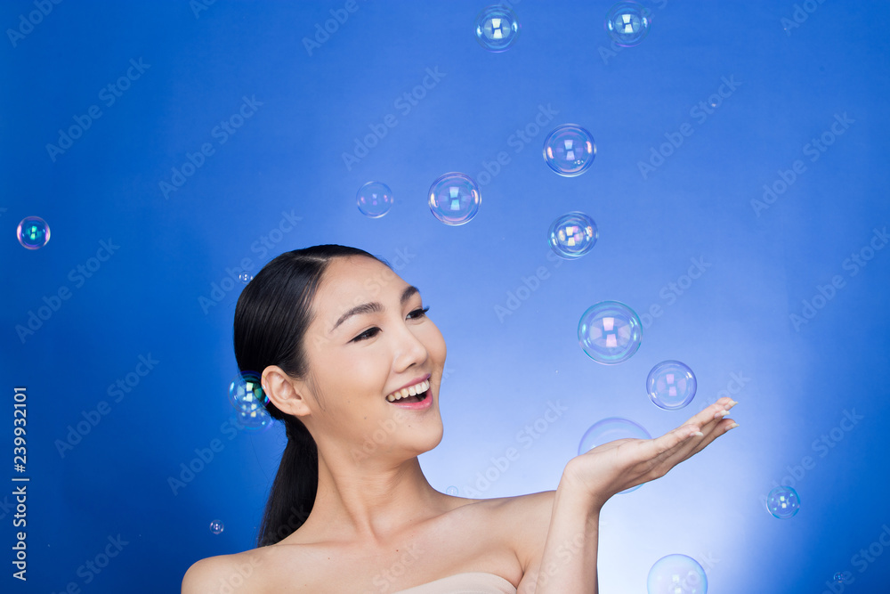 Asian Beautiful Woman black hair blow many bubbles soap in the air over studio lighting blue background, concept Play fun Joyful nice skin, empty copy space for advertising Asian Beautiful Woman black hair blow many bubbles soap in the air over studio lighting blue background, concept Play fun Joyful nice skin, empty copy space for advertising