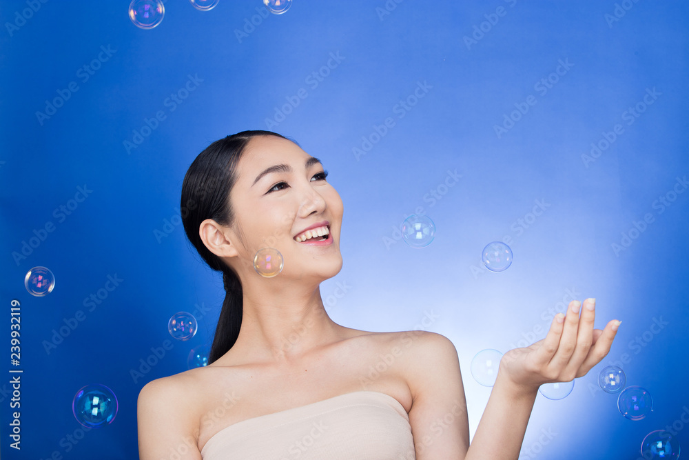 Asian Beautiful Woman black hair blow many bubbles soap in the air over studio lighting blue background, concept Play fun Joyful nice skin, empty copy space for advertising Asian Beautiful Woman black hair blow many bubbles soap in the air over studio lighting blue background, concept Play fun Joyful nice skin, empty copy space for advertising