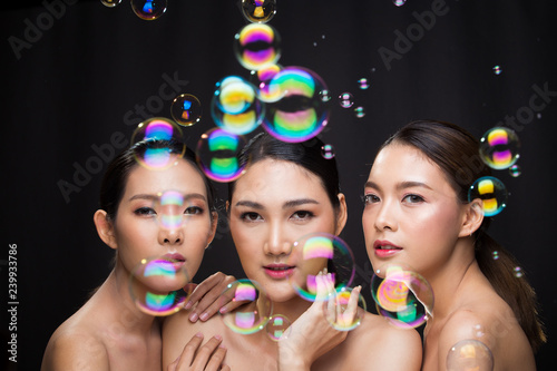 Group Three Beautiful Asian Long straight black hair tan skin women portrait in open naked shoulder, fashion make up, studio lighting dark background Empty copy space, concept bath skincare product