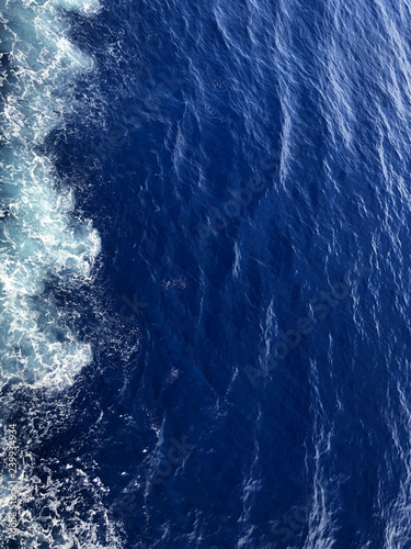 Top view of the blue water of the Andriatic Sea. Background, texture of water. Cropped shot, vertical, empty space, concept of leisure and travel. photo