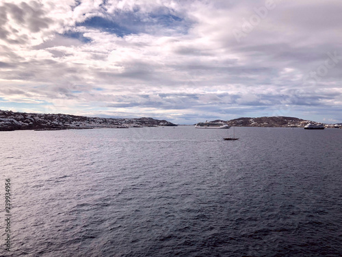View of the island of Mykonos Greece from the sea. Cloudy clouds in the sky over the island. Clipped shot, horizontal, empty space, concept of leisure and travel