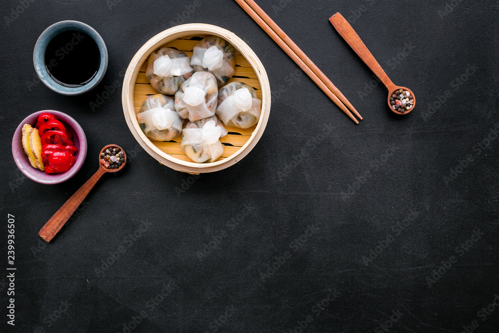 Dim sums with red pepper and vegetables with sticks and black tea in Chinese restaurant on black background top view mockup Dim sums with red pepper and vegetables with sticks and black tea in Chinese restaurant on black background top view mockup