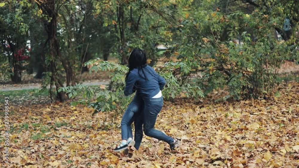 Happy mother and her Little daughter having fun in autumn park. Young family throwing leaves and laughing. Slow-motion Happy mother and her Little daughter having fun in autumn park. Young family throwing leaves and laughing. Slow-motion