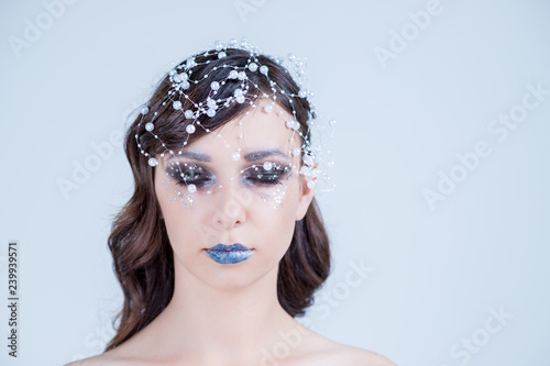 Elegant young lady with evening make up and beads on her head. Make-up of woman eye with shiny eyeshadow. Beauty portrait,silver blue lips, curls. Creative Professional makeup.Closed eyes.Copy space