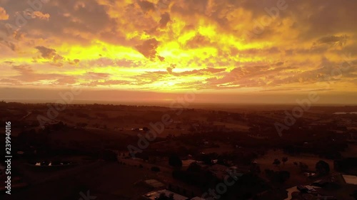 Forward moving aerial shot of the bright orange glow of the sun setting on the horizon in rural Australia. photo