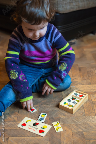 Child playing with fruits painted on wooden blocks.