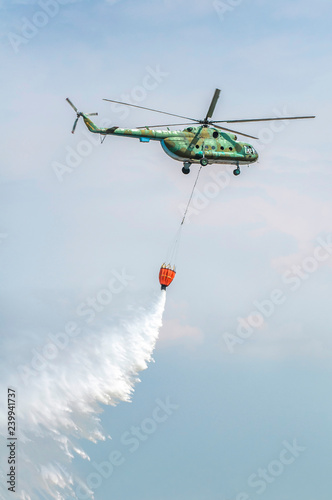 Billede på lærred Green firefighting helicopter transporting water.