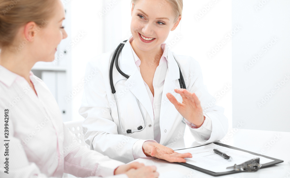 Doctor and patient talking in hospital office while sitting at the desk. Health care and client service in medicine Doctor and patient talking in hospital office while sitting at the desk. Health care and client service in medicine