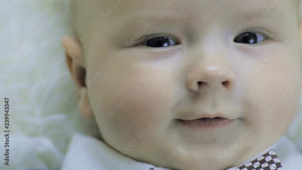 Close-up of a six-month-old boy lying on a white blanket in a beautiful suit. Close-up of a six-month-old boy lying on a white blanket in a beautiful suit.