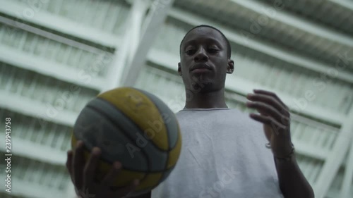 African boy tosses over the ball from hand to hand at the indoor basketball playground photo