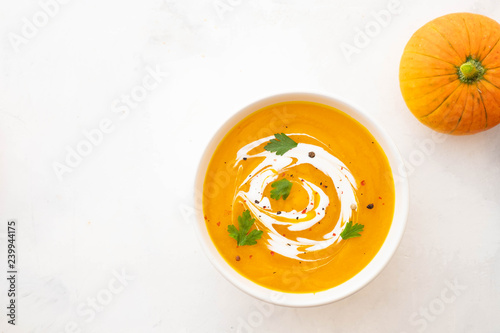 Pumpkin soup with cream and pumpkin seeds isolated on white background. Autumn concept.