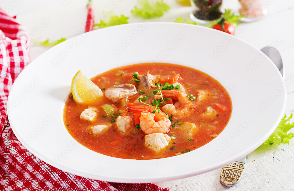 Brazilian food: Moqueca capixaba of fish and bell peppers in spicy coconut sauce in a plate on a white wooden table. Brazilian fish stew. Brazilian food: Moqueca capixaba of fish and bell peppers in spicy coconut sauce in a plate on a white wooden table. Brazilian fish stew.