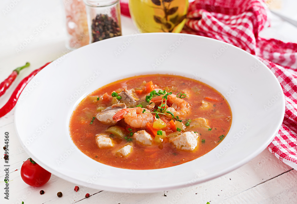 Brazilian food: Moqueca capixaba of fish and bell peppers in spicy coconut sauce  in a plate on a white wooden table. Brazilian fish stew.