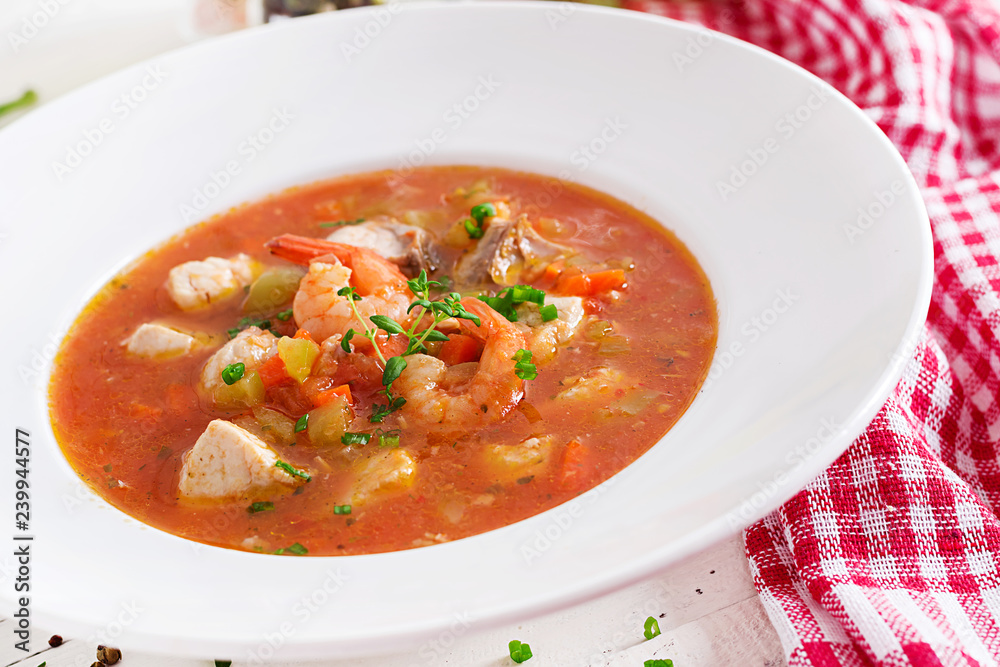 Brazilian food: Moqueca capixaba of fish and bell peppers in spicy coconut sauce in a plate on a white wooden table. Brazilian fish stew. Brazilian food: Moqueca capixaba of fish and bell peppers in spicy coconut sauce in a plate on a white wooden table. Brazilian fish stew.