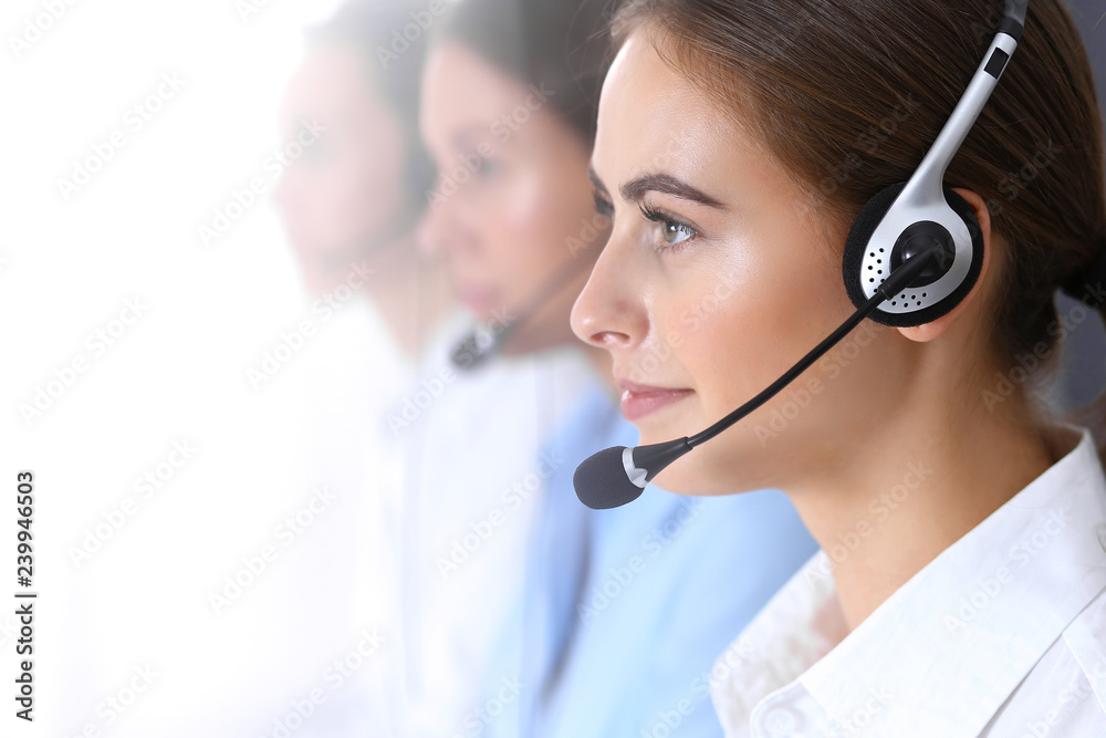 Call center. Group of operators at work. Focus at beautiful business woman in headset Call center. Group of operators at work. Focus at beautiful business woman in headset