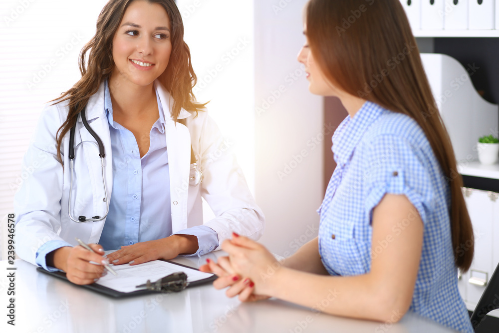 Doctor and happy patient talking while sitting at the desk. The physician or therapist discussing healthy lifestyle. Health care, medicine and patient service concept Doctor and happy patient talking while sitting at the desk. The physician or therapist discussing healthy lifestyle. Health care, medicine and patient service concept