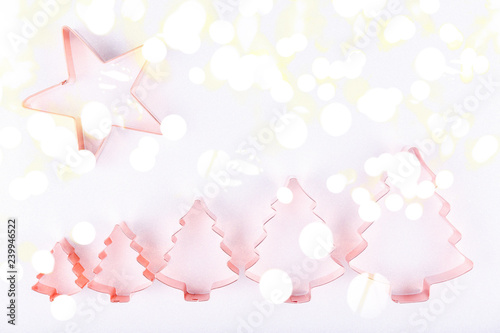 Flatlay with star and row of holiday tree copper cookie cutters on white sparkling background. Holiday, Christmas and New Year concept. Cozy homey details