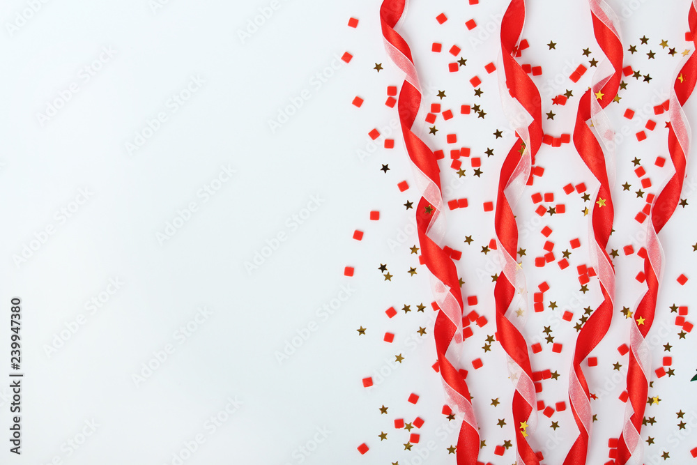 Red satin ribbons and confetti background with copy space