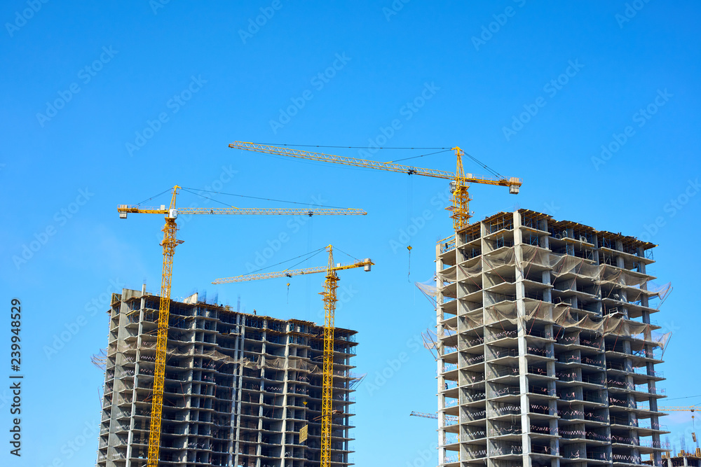 Building cranes and building under construction against sky. Building cranes and building under construction against sky.
