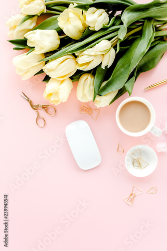 Female home office desk. Workspace with yellow tulip flowers, stationery, accessories on pink background.  Flat lay, top view.