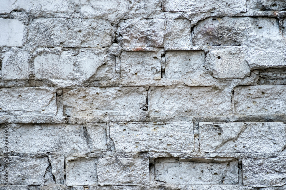 The white wall with the hollows in the bricks with cracks and cement mortar between them. Background The white wall with the hollows in the bricks with cracks and cement mortar between them. Background