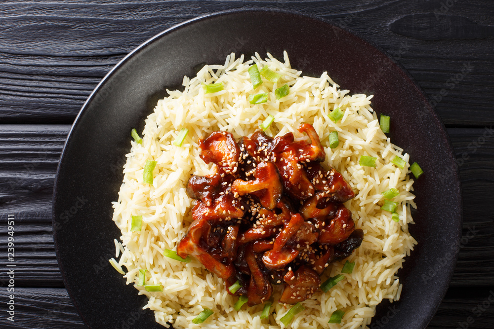 Delicious fried shiitake mushrooms with garlic and sesame seeds served with rice closeup on a plate. Horizontal top view Delicious fried shiitake mushrooms with garlic and sesame seeds served with rice closeup on a plate. Horizontal top view