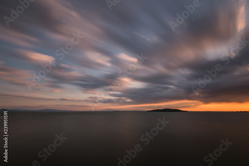 Beautiful wide angle, long exposure view of a lake at sunset, with an huge sky with moving clouds