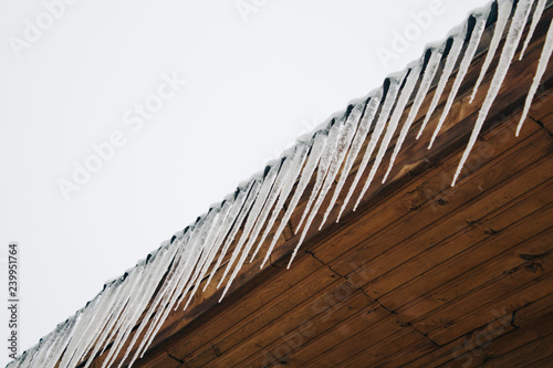 frozen icicles on the roof of the wooden house, top floor wooden mansion. Icy weather winter scene