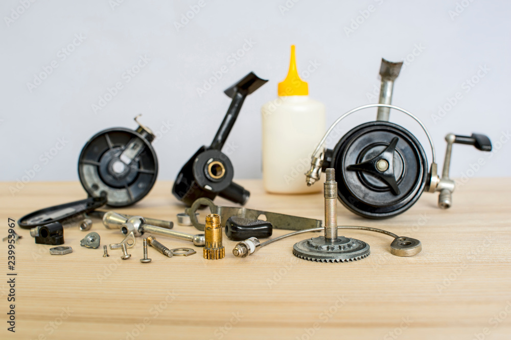 A fishing spinning reel as a whole and a second similar completely  disassembled. Concept: parts of a whole. Preparation for the fishing  season: prevention and application of lubrication. Stock Photo