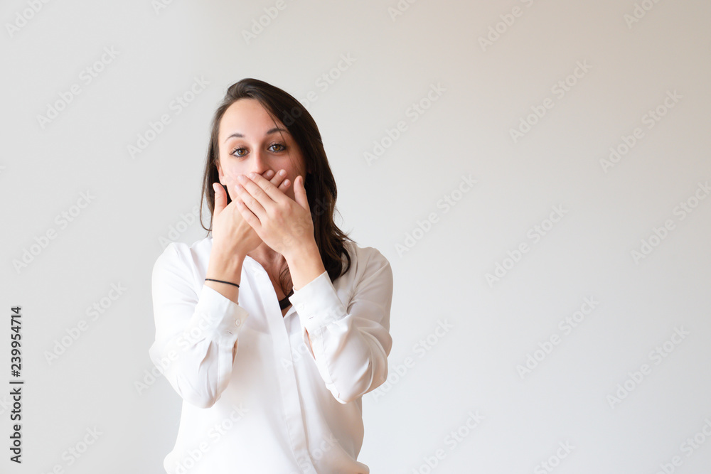 Excited girl keeping secret. Beautiful young woman covering mouth with both hands. Silence or gossip concept Excited girl keeping secret. Beautiful young woman covering mouth with both hands. Silence or gossip concept