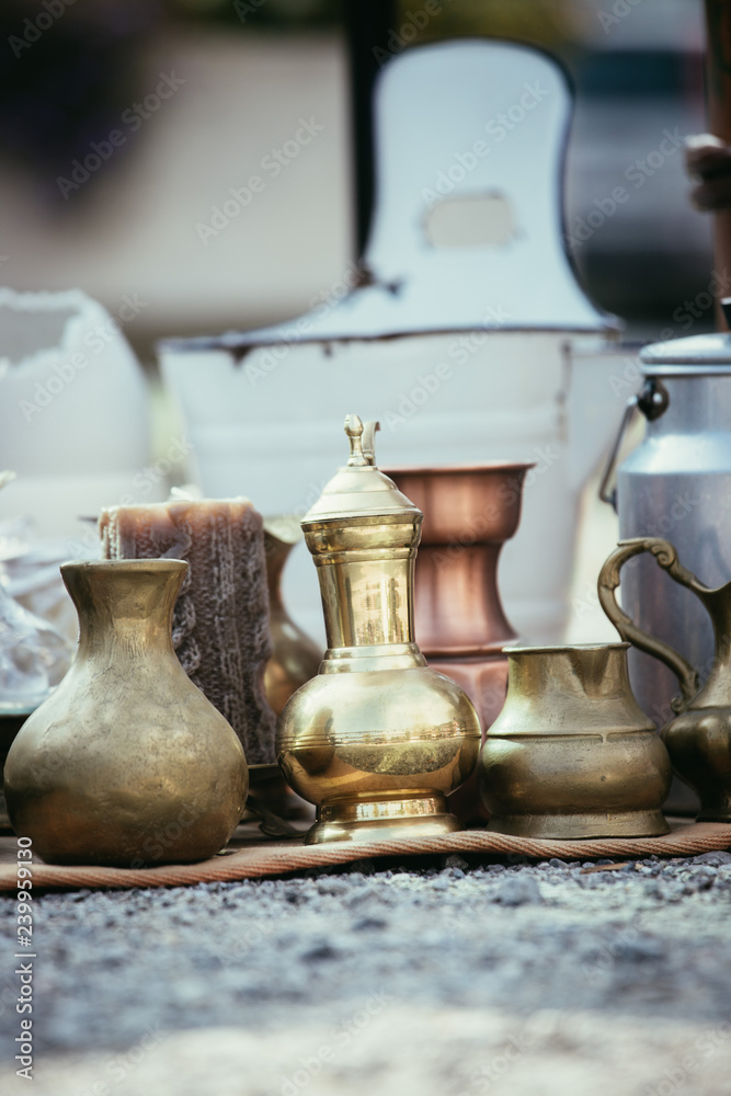 Antique teapots, creamer and other utensils at a flea market. Old metal tableware at a garage sale. Antique teapots, creamer and other utensils at a flea market. Old metal tableware at a garage sale.