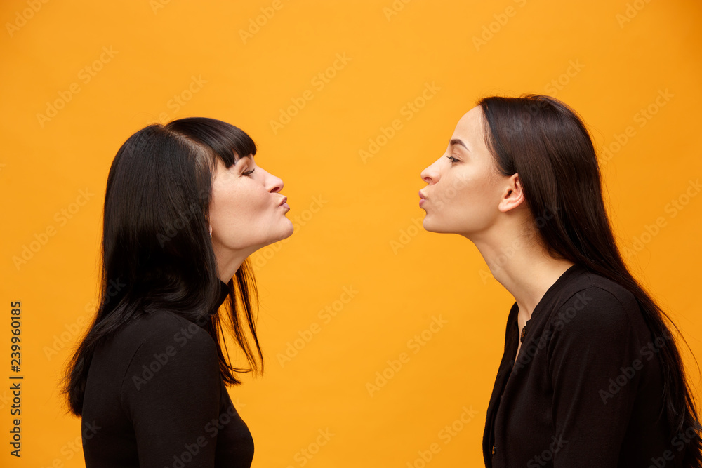 A portrait of a happy mother and daughter at studio on gold background. Trendy colors. Human positive emotions and facial expressions concept. Profile view A portrait of a happy mother and daughter at studio on gold background. Trendy colors. Human positive emotions and facial expressions concept. Profile view