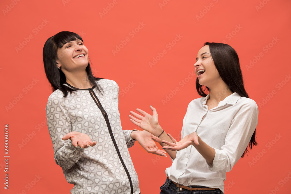 A portrait of a surprised mother and daughter at studio on living coral background. Trendy colors. Human positive emotions and facial expressions concept A portrait of a surprised mother and daughter at studio on living coral background. Trendy colors. Human positive emotions and facial expressions concept