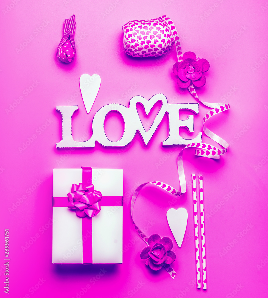 Fototapeta premium Creative flat lay composition with word love, gift box and decoration on neon color background , top view. Valentines day greeting and shopping sale, abstract love symbol layout