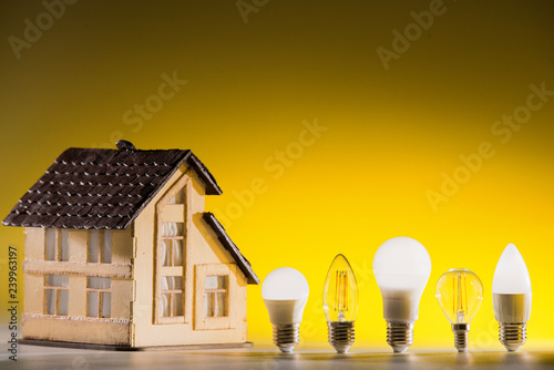 Led lamps stand near the layout of the house on a yellow background