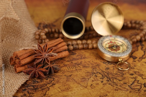Fototapeta Naklejka Na Ścianę i Meble -  
Vintage compass with spyglass telescope and cinnamon spices on an old world map - trade and explorer concept
