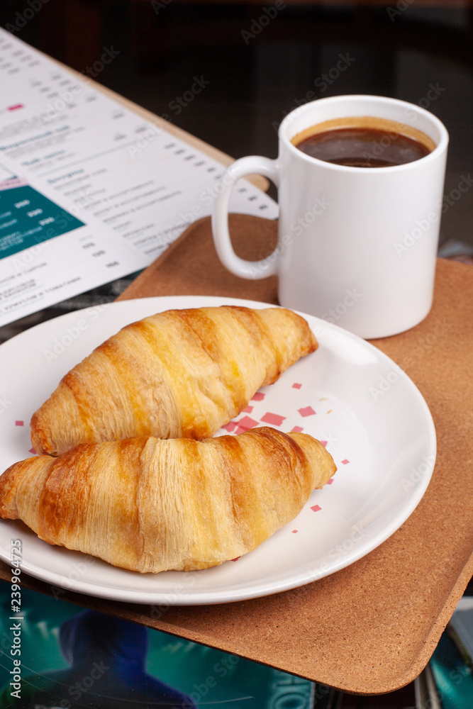 Two delicious croissants with a cup of coffee on the coffee table Two delicious croissants with a cup of coffee on the coffee table