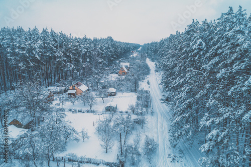 View from above of village lokated in pine forest in snowy winter photo