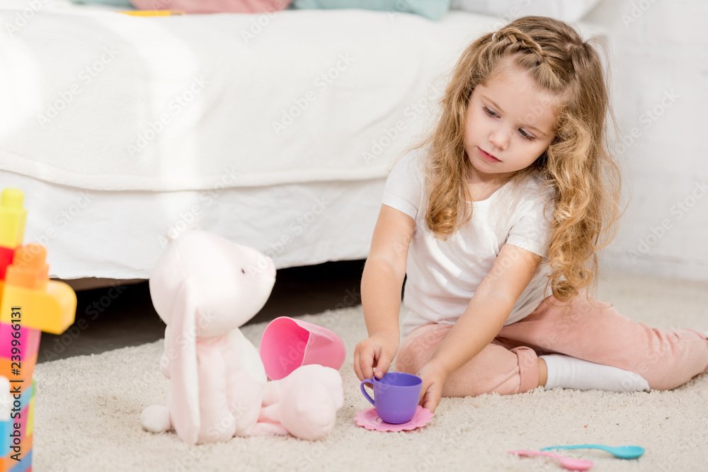 adorable child playing with rabbit toy and plastic cups in children room adorable child playing with rabbit toy and plastic cups in children room