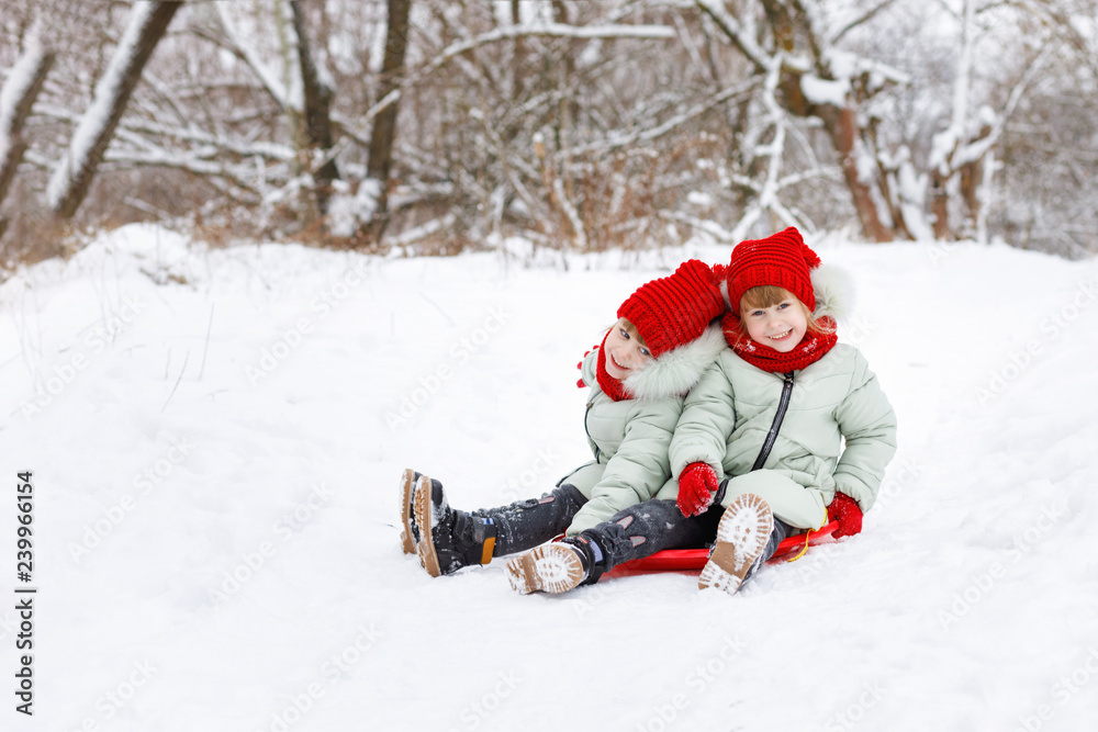 Children twins are sitting on the snowy ground. Children twins are sitting on the snowy ground.